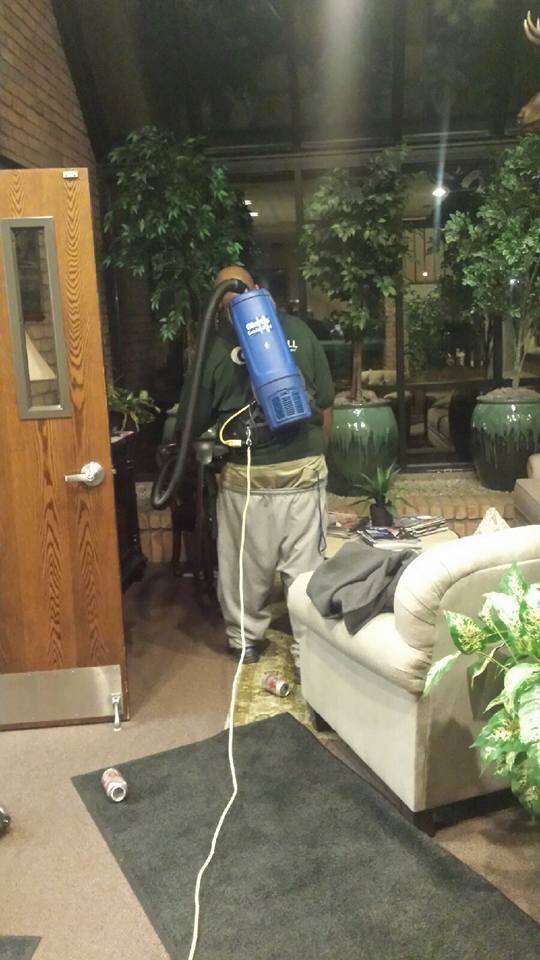 A cleaner vacuuming an office floor