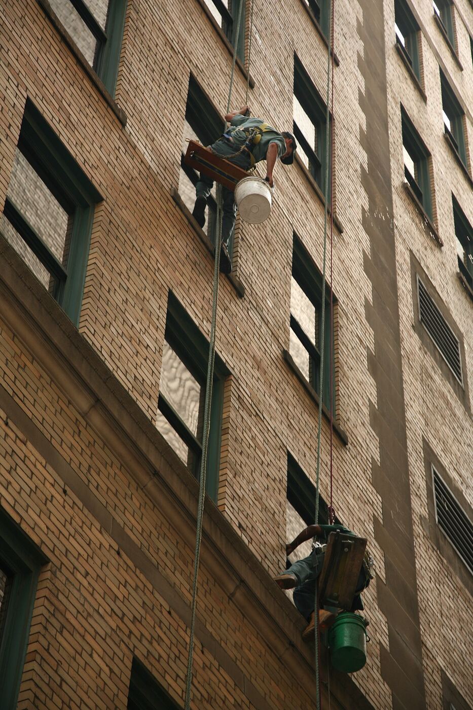A worker cleaning the windows of a building from the outside
